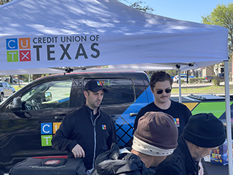 A group of people standing by a Credit Union of Texas turck and event tent